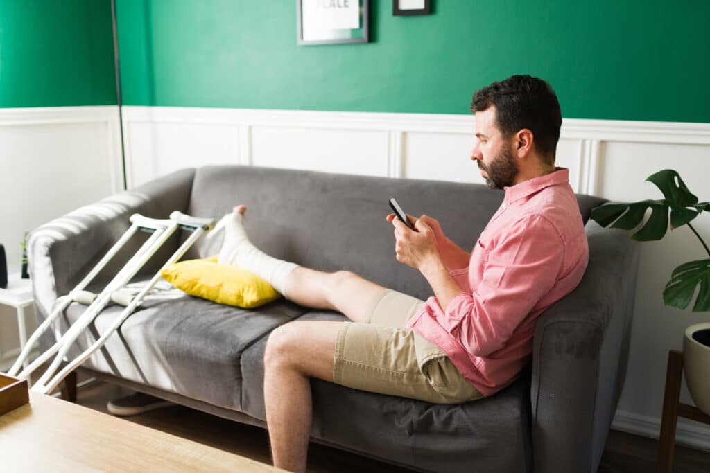 Man on crutches looking at his phone