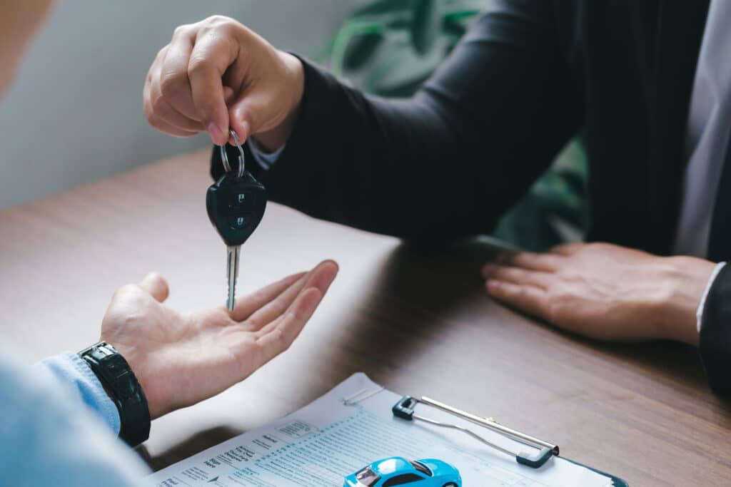 Close up view Hand of car salesman giving car key to the customers after who signed the purchase contract legally, Successful completion of car sales, Purchase contract.