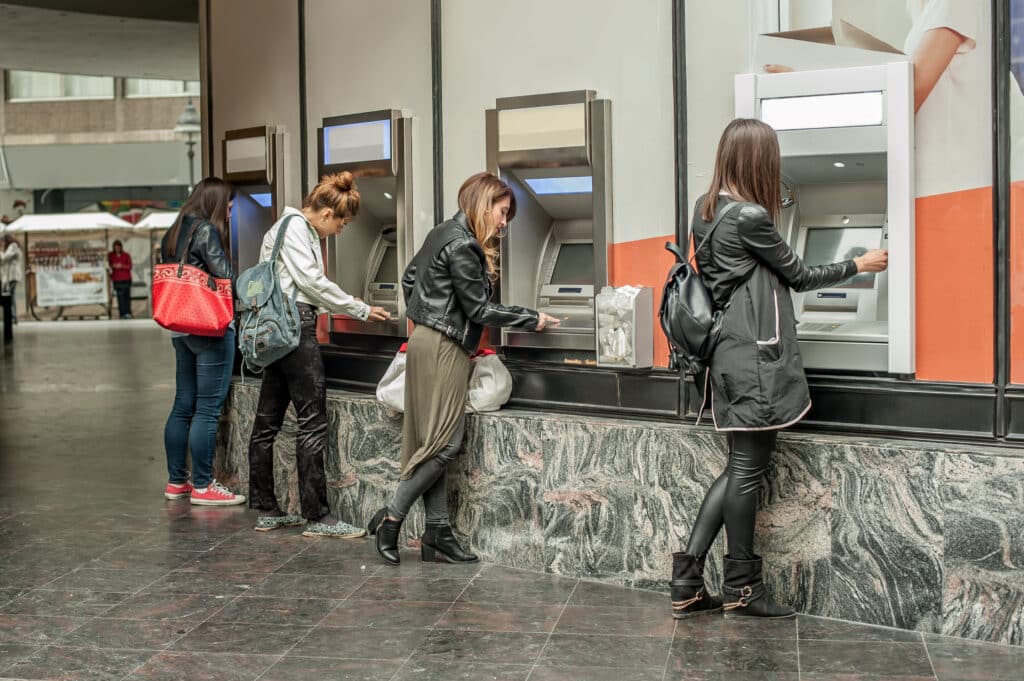 Four girl friends withdrawing money from at an ATM