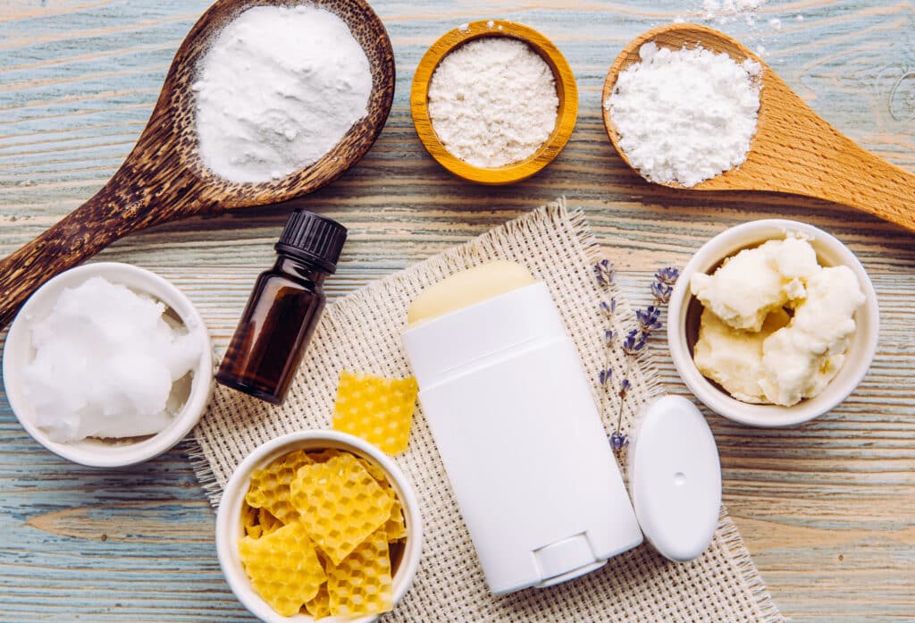 diy beauty products. Making homemade deodorant stick with all natural ingredients concept. Blue wooden background. Ingredients: arrowroot powder, baking soda, beeswax, shea butter, essential oil, cornstarch, coconut oil.