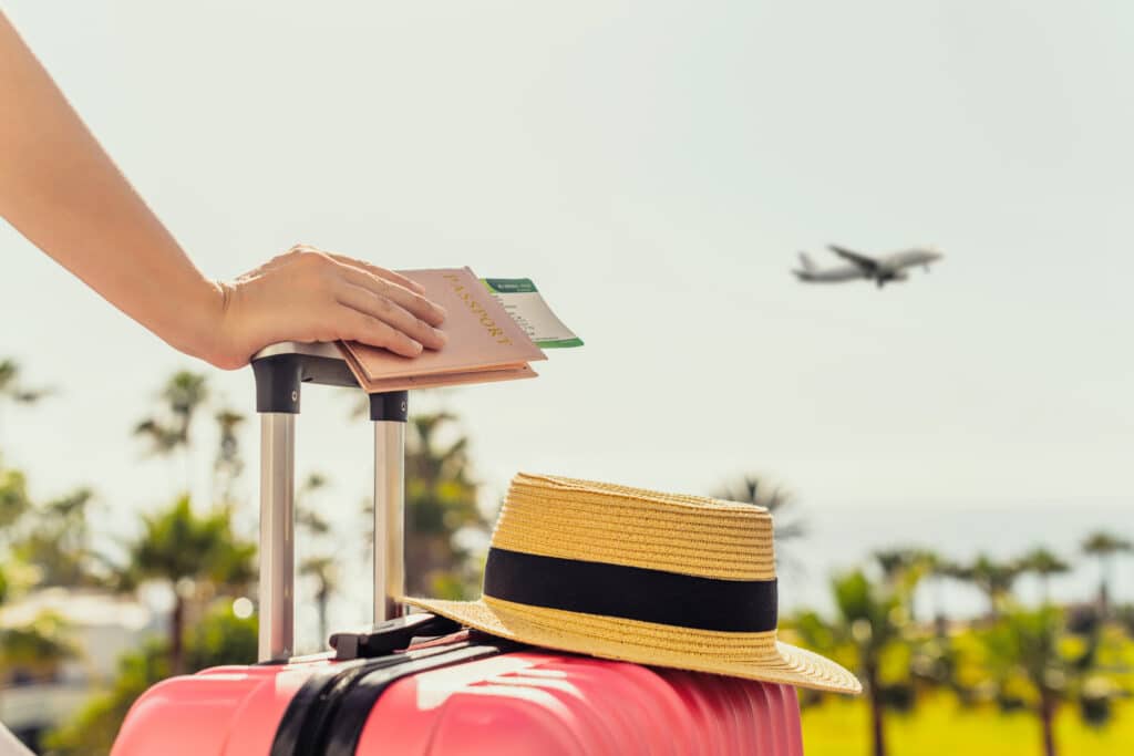 Woman with pink suitcase and passport, travel insurance.