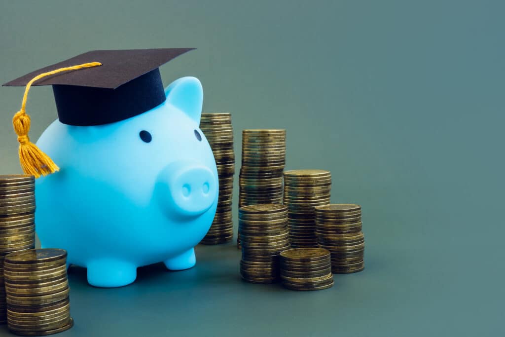 529 plan, for college. blue pig with graduation cap and stacks of coins.