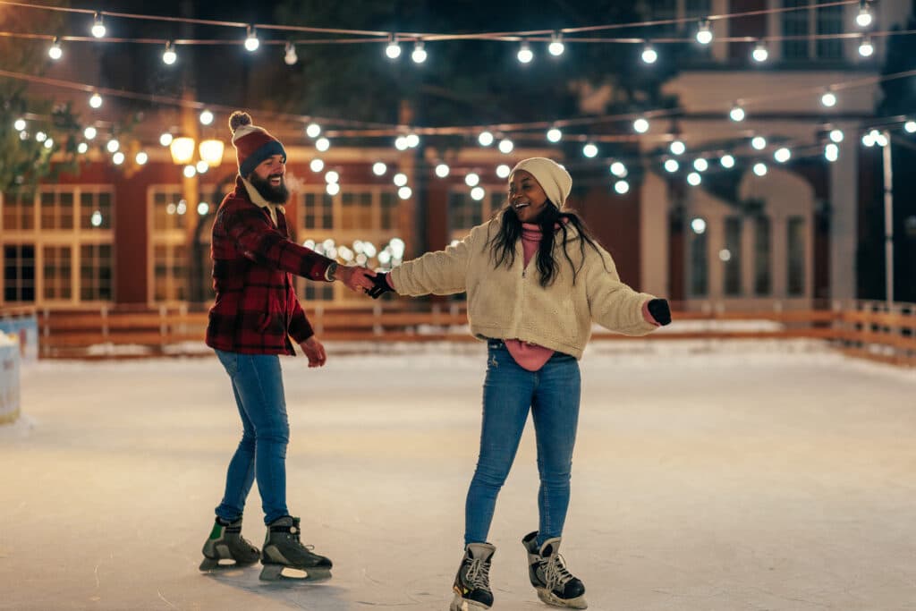 date night: couple ice skating with lights strung overhead.