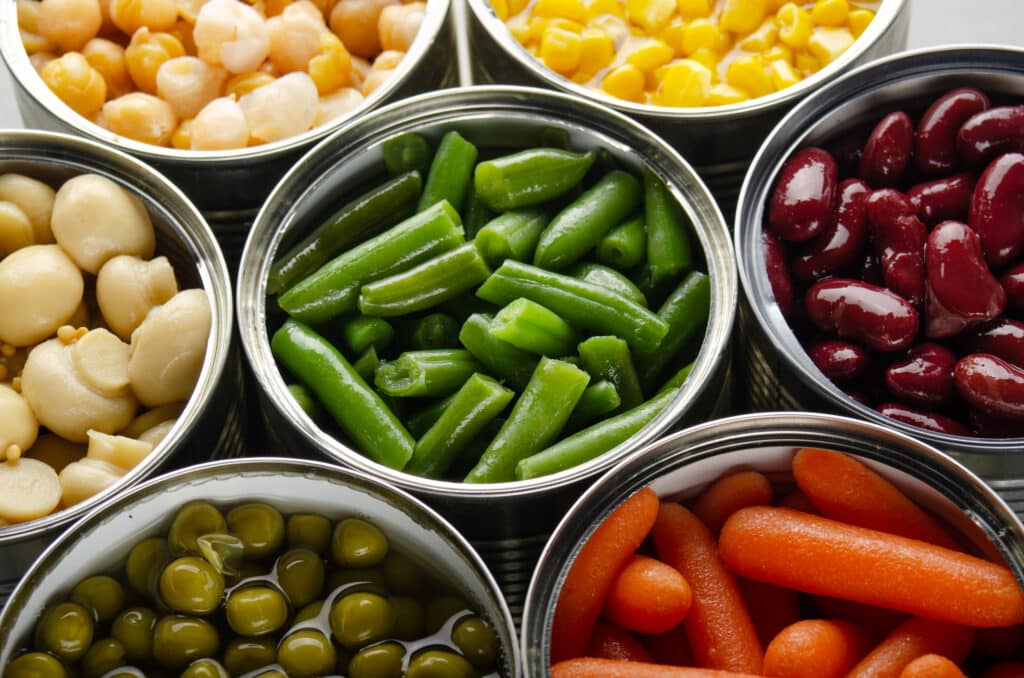 affordable convenience foods Canned vegetables in opened tin cans on kitchen table. Non-perishable long shelf life foods background