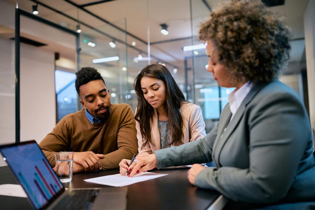 financial advisor and young black couple sitting at a table