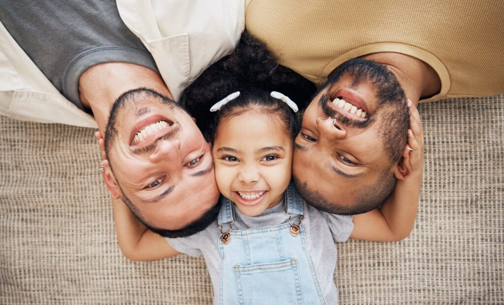 LGBT family—little girl with two dads, smiling.