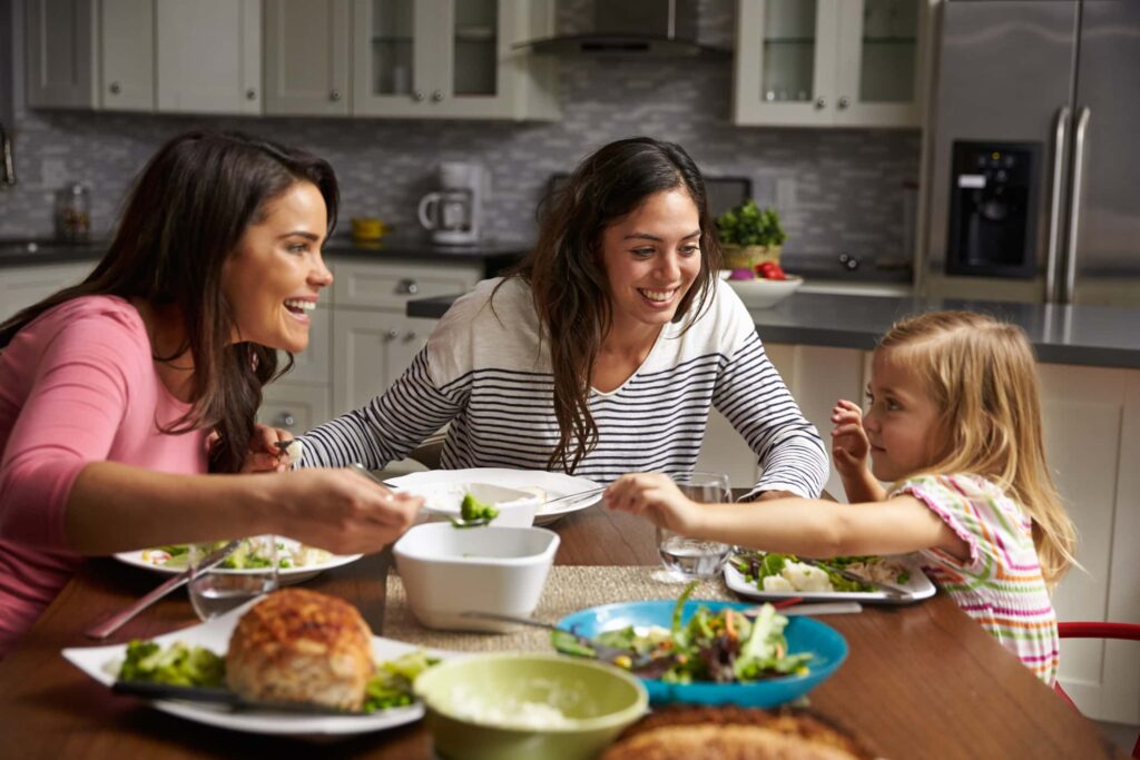 LGBT family sitting at table, two moms and a little girl.