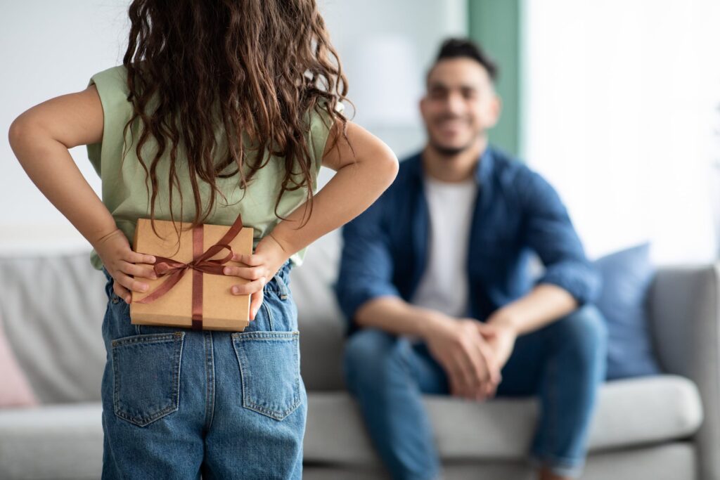 little girl with father's day gift, approaching her dad.