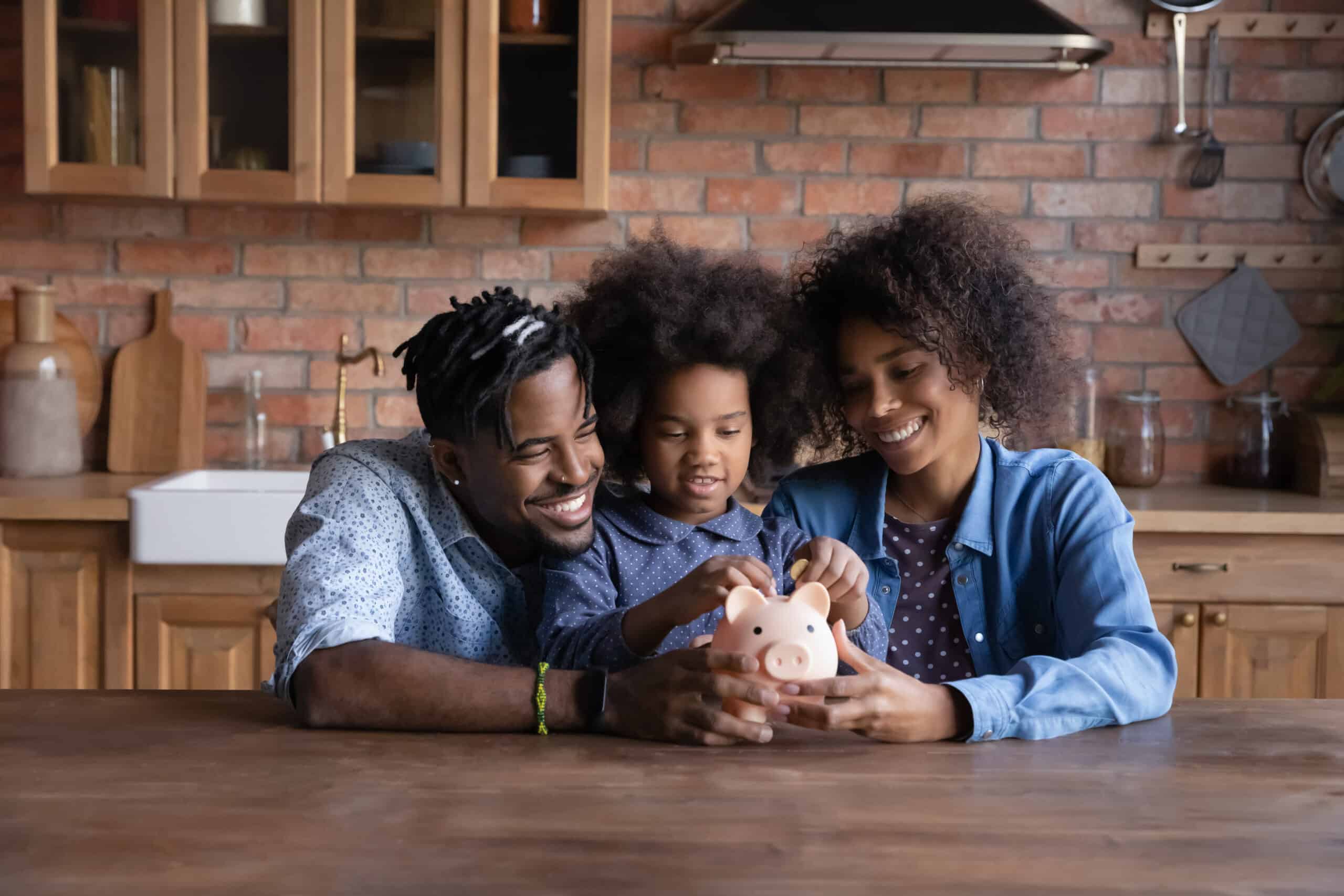 savings challenge: Smiling young African American family with daughter save money in piggybank feel provident economical about finances. Happy biracial parents with ethnic child make financial investment for future.