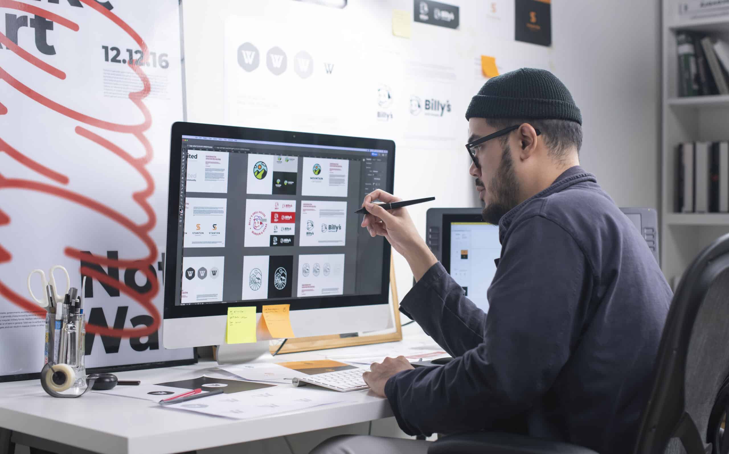 freelancer graphic designer man sitting at computer with grey shirt and beanie.
