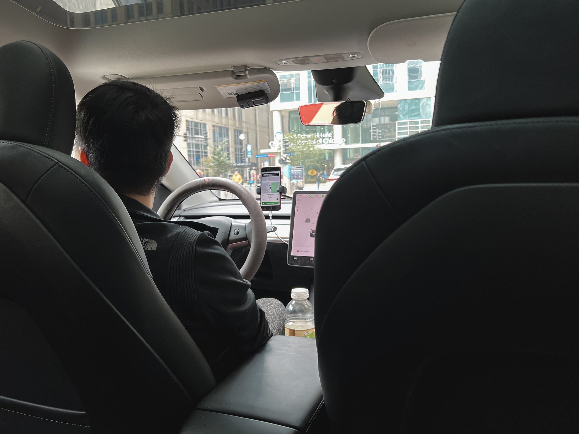 Lyft and Uber driver in his car, view from the backseat.