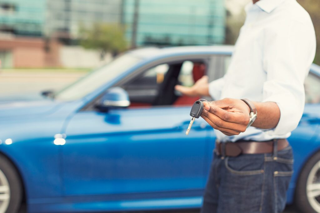 sell your car—man standing in front of blue car.