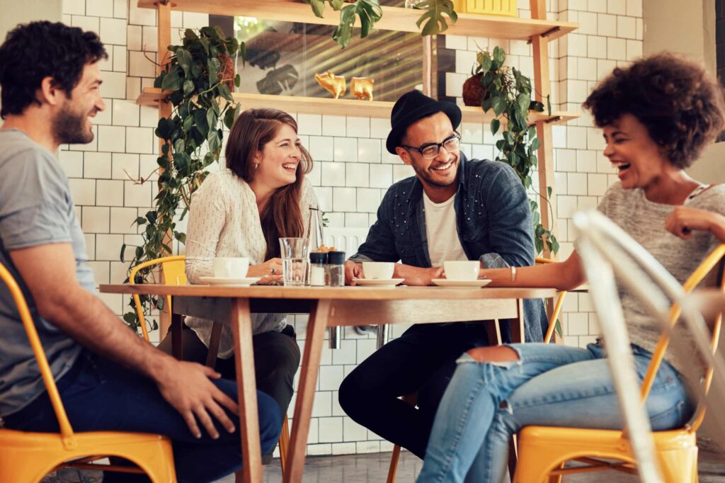 talk about money. Young people having a great time in cafe. Friends smiling and sitting in a coffee shop, drinking coffee and enjoying together.