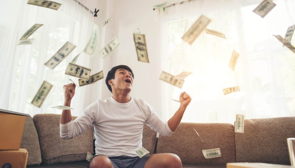 Man sitting on the couch with money falling