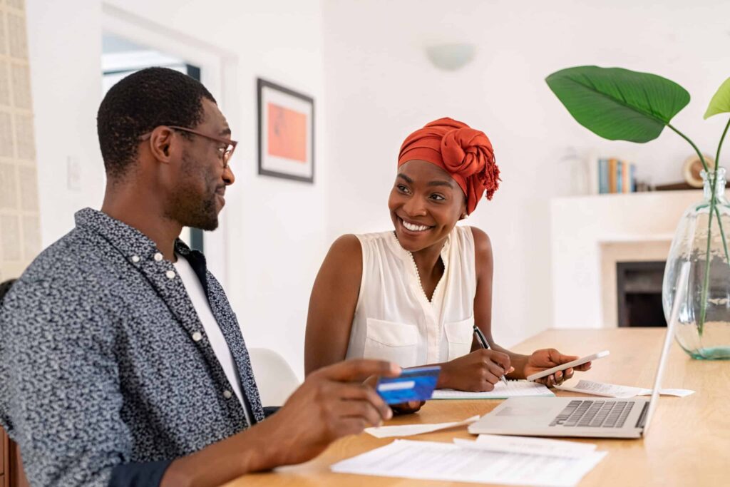 financial plan: couple sitting at computer, smiling at each other, planning out finances.