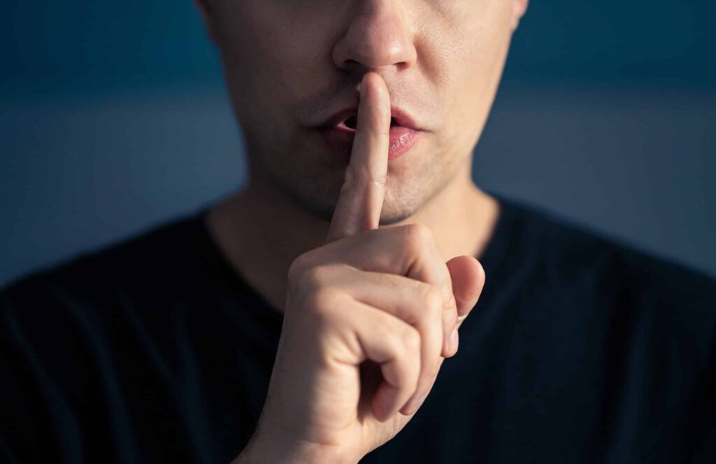 money secrets. Secret and silence. Quiet silent shh gesture with finger on lips. Man doing expression with hand on mouth. Taboo topic, censorship or freedom or speech. Conspiracy theory. Confidential talk.