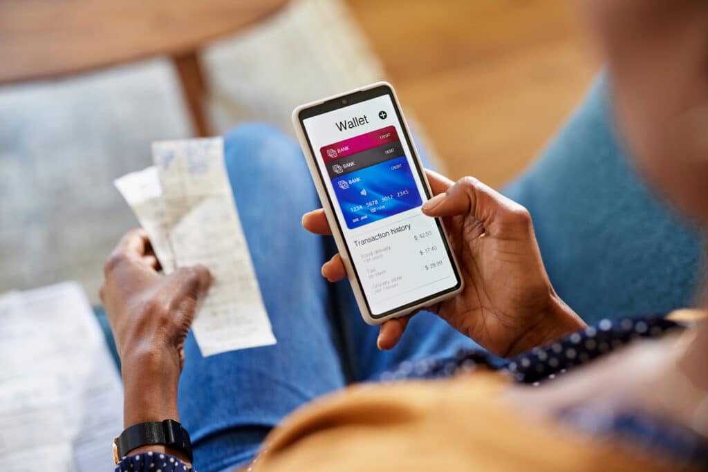 Digital wallets. Hands of african american woman using mobile phone to check payments, account statement and transaction history. Close up of black woman hand using smartphone for checking the balance of her online wallet. Checking expenses of the month on smart phone by internet banking.