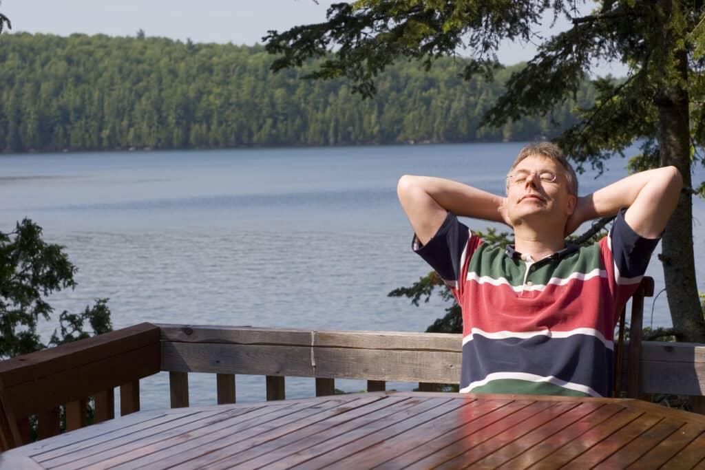 FIRE movement. Man who retired early, relaxing at a table with lake in the background.