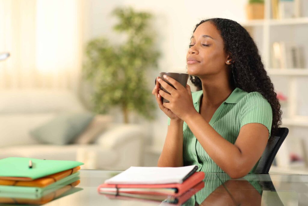 financial self care. young black woman sitting with cup of coffee and books.