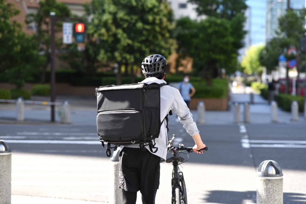 job scam, food delivery courier walking with bike.