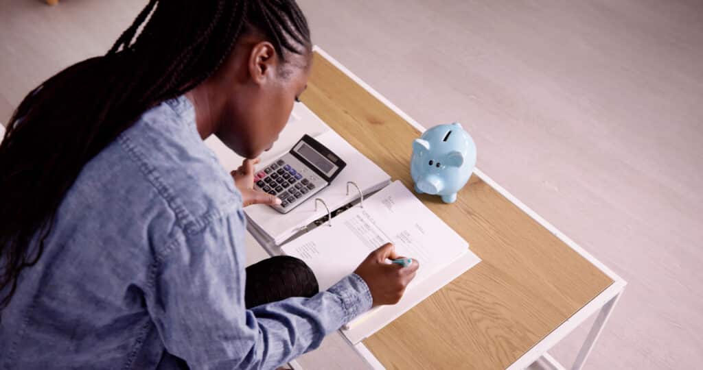 budget types. Young African Woman Calculating Invoice With Calculator