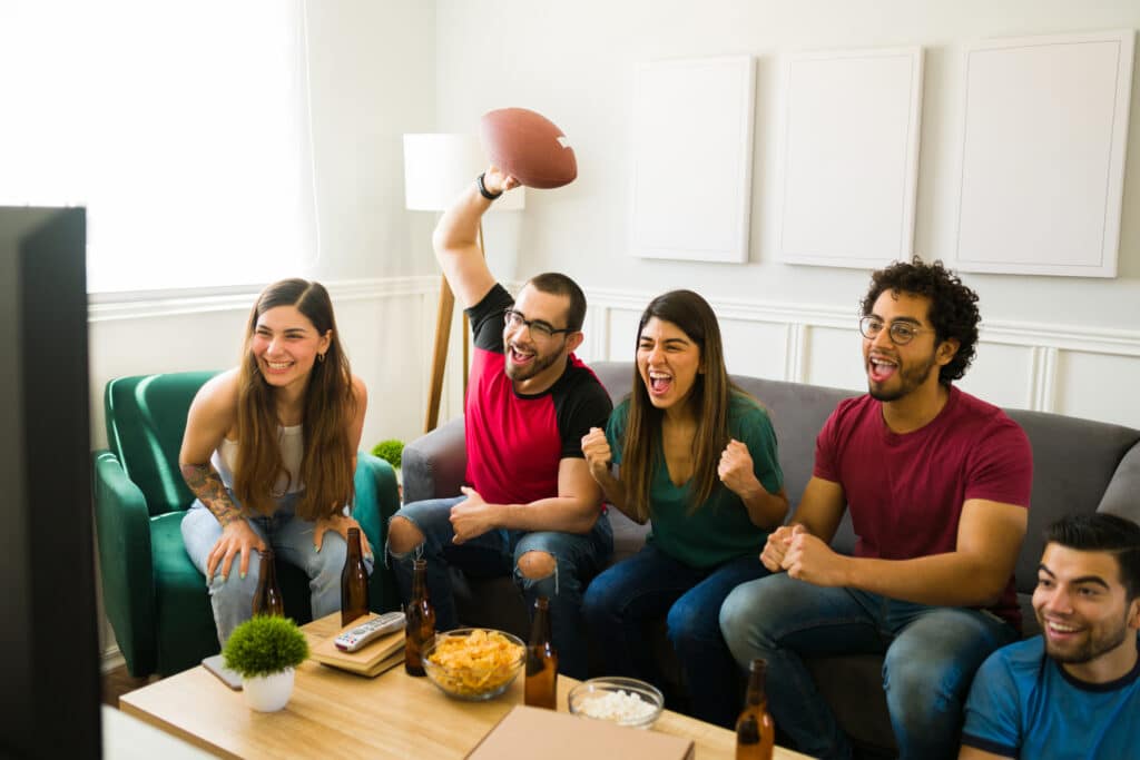 football with no cable. Cheerful group of friends cheering and having fun while watching a football game on tv