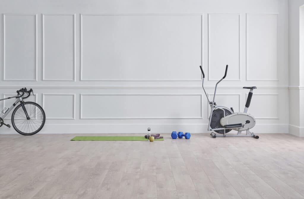 home gym. Sport in the room, classic white wall, bike, green gym mat, dumbbell and water style.