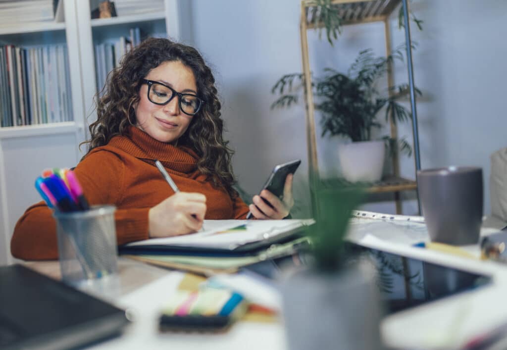 50/50 budget. Woman holding phone in her hands, calculating family budget at home.