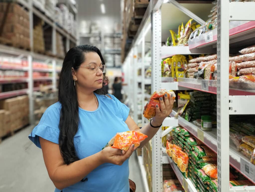 priority-based budget. The housewife chooses products and food for dinner at home from the back of the shelves in a supermarket. Check and look for healthy products to help your family eat well.