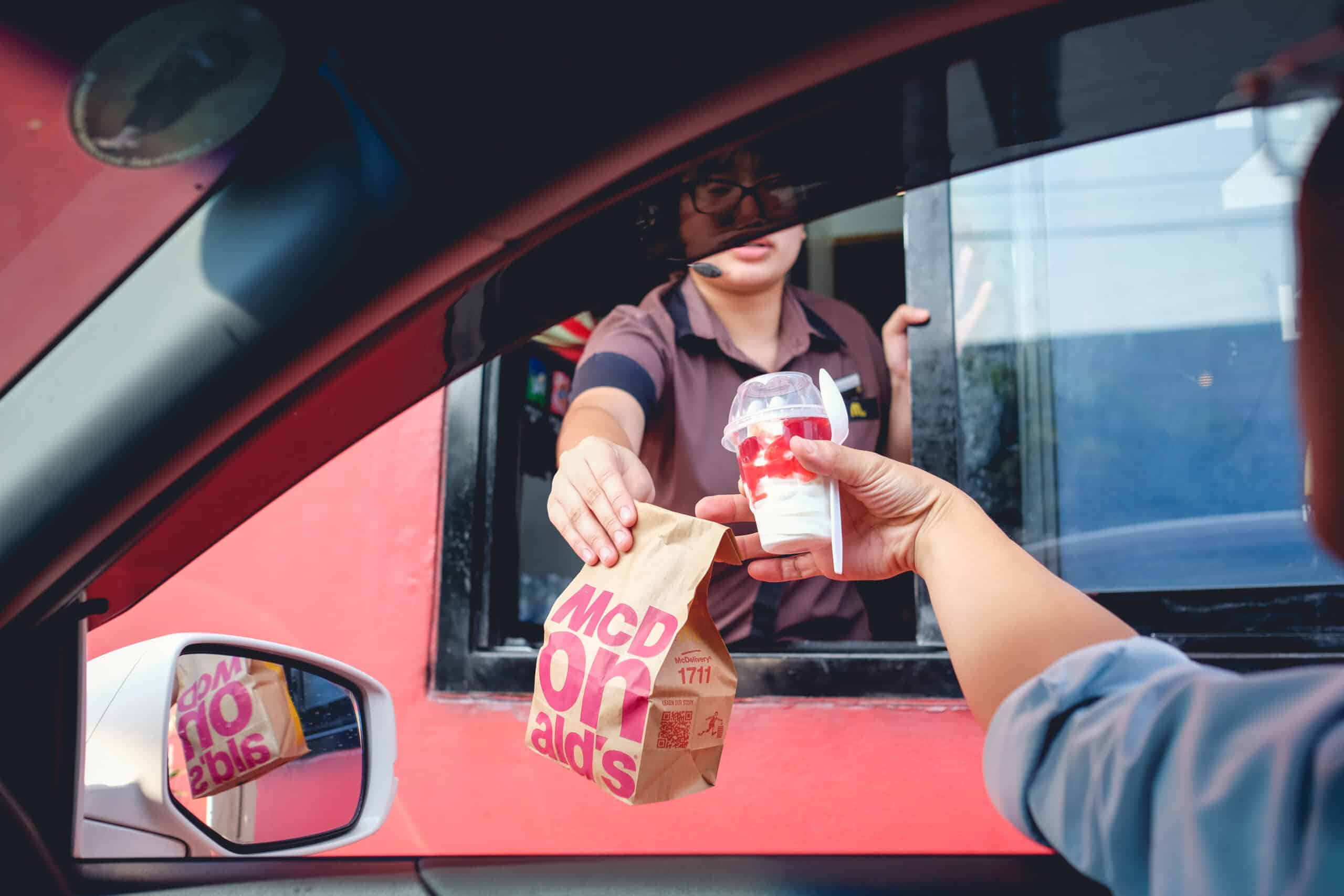 fast food. Employee handing bag to customer in drive-through.