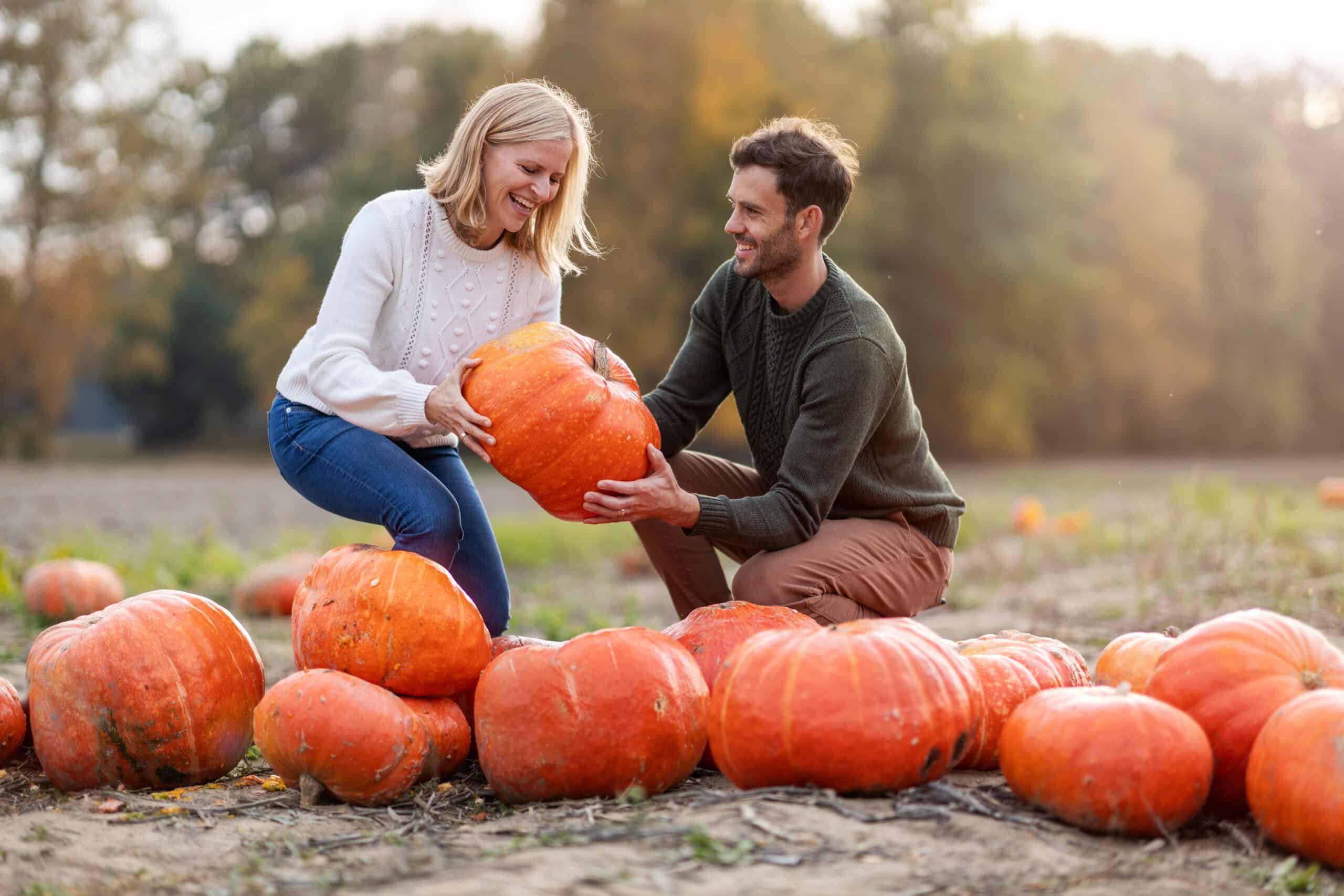 fall date. Happy young couple in pumpkin patch field