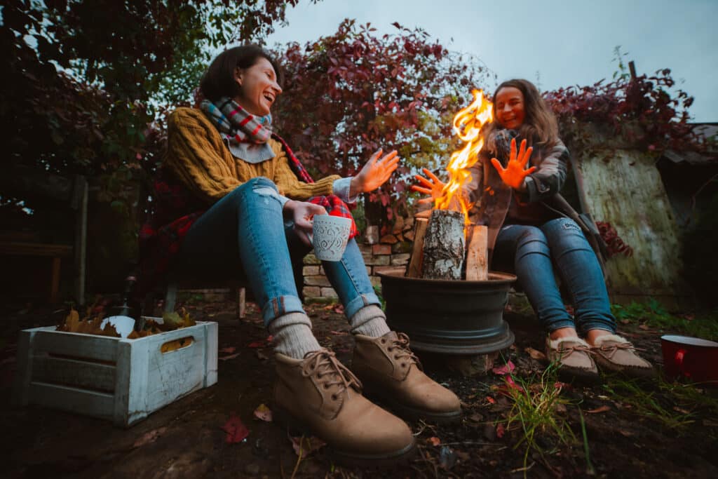 fall entertaining. two friends relax comfortably and drink wine on an autumn evening in the open air by the fire in the backyard. The concept of autumn, friendship. top view of the legs