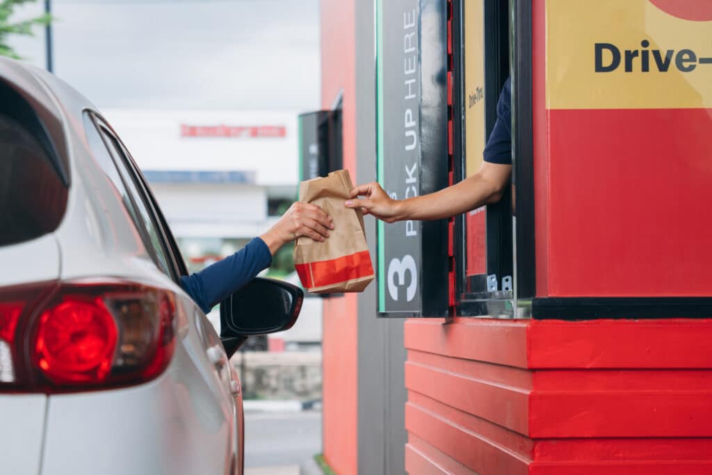 fast food. Young Man receiving coffee at drive thru counter., Drive thru and take away for protect covid19.