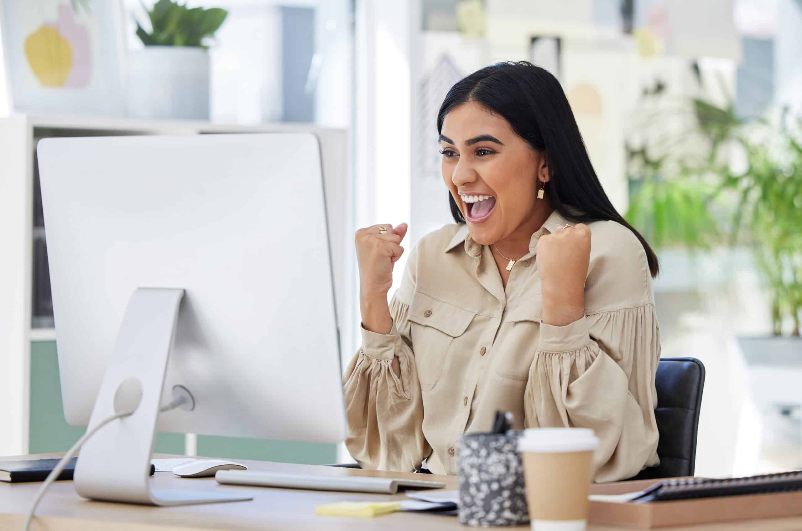 financial freedom. Business woman, happy and excited at her office computer, celebration of great news in email. Financial freedom, a deal and corporate success for startup employee after first sale on company website.