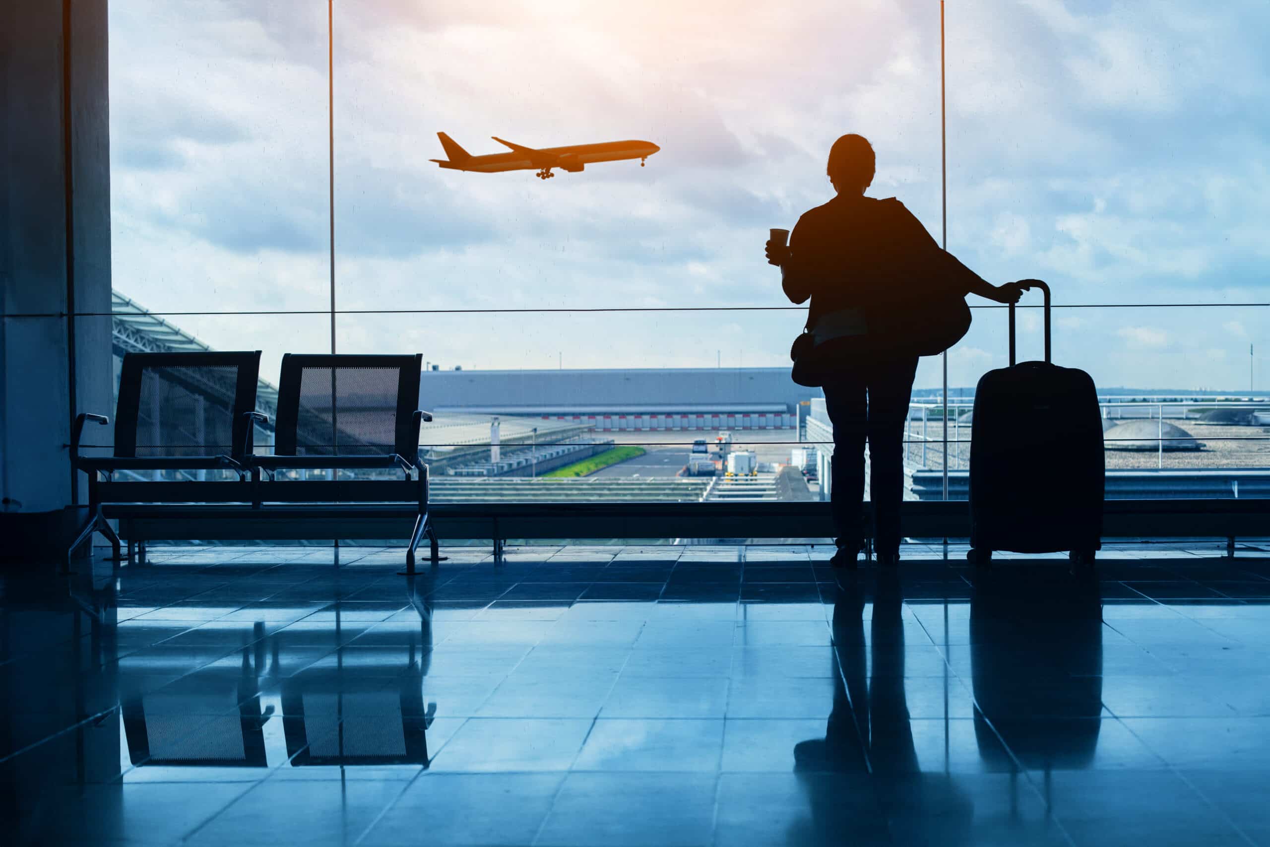 uplift. travel by plane, woman passenger waiting in airport, silhouette of passenger in airport watching aircraft taking off