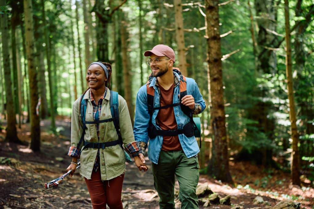 no-spend weekend. Happy man and his African American girlfriend hiking in the forest.