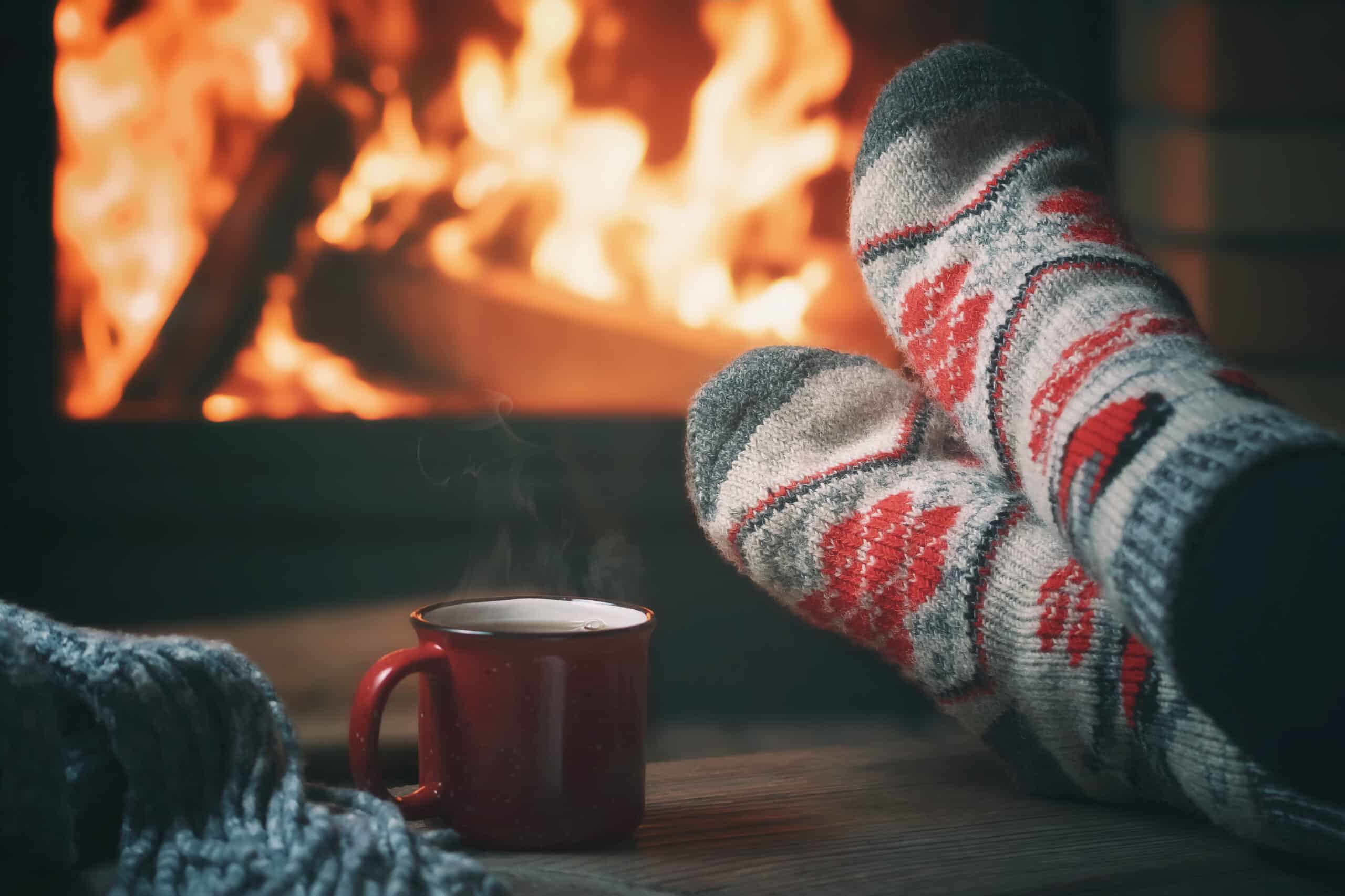 self-care.Girl resting and warming her feet by a burning fireplace in a country house on a winter evening. Selective focus.