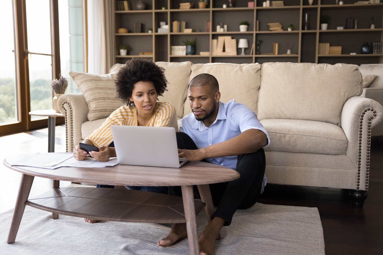 financial assessment. African couple sit in living room discuss receipts, control family budget, calculate household bills to pay, utility expenses, make payment via e-bank app on laptop, accounting, money control concept