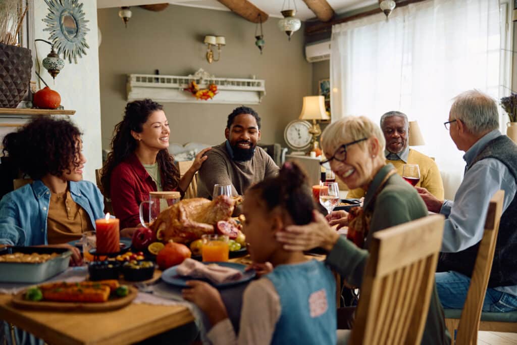 How to host Thanksgiving on a budget. family gathered around a festive holiday table.