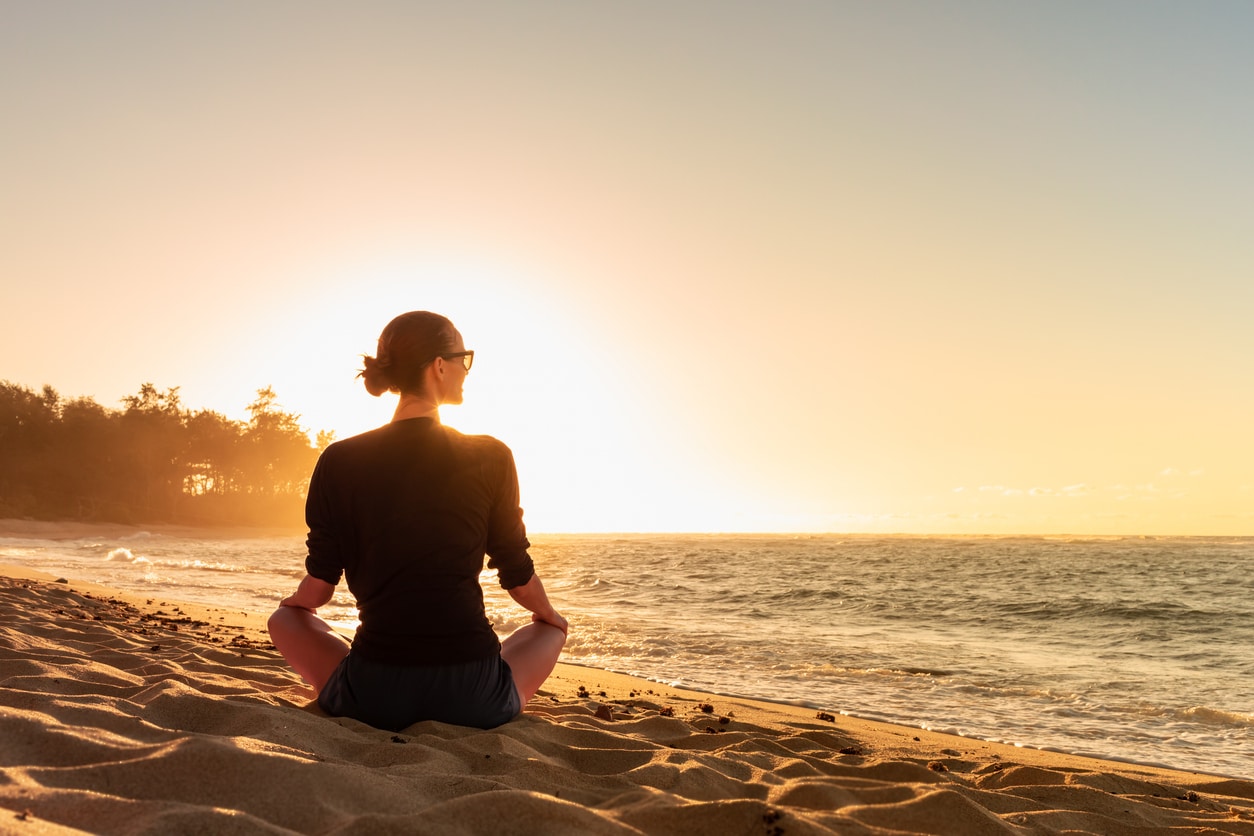 new year. Young woman looking out to the ocean sunrise finding peace happiness in nature.