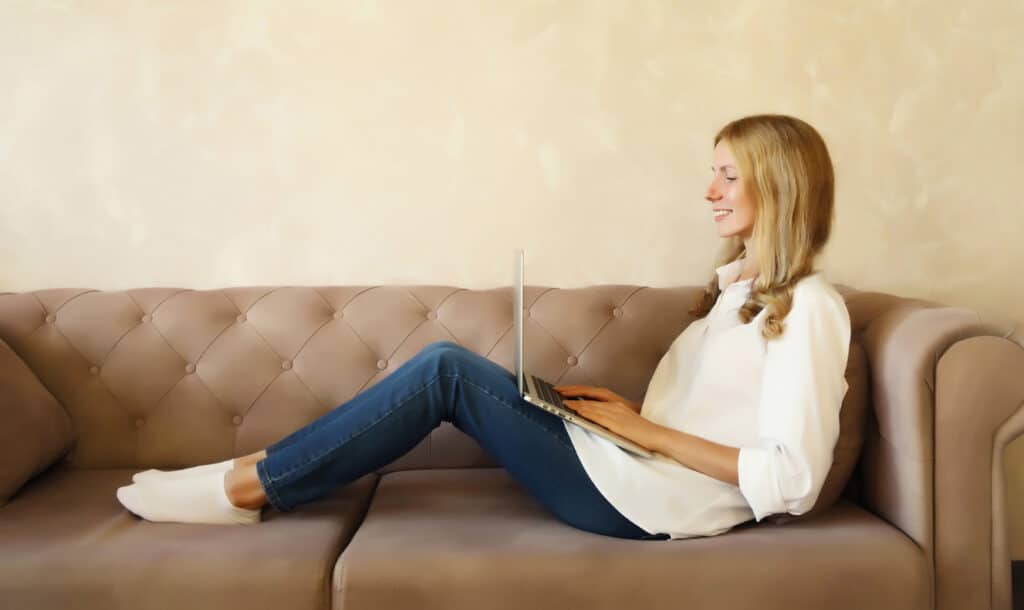 chatgpt. Blond woman on brown couch with computer.