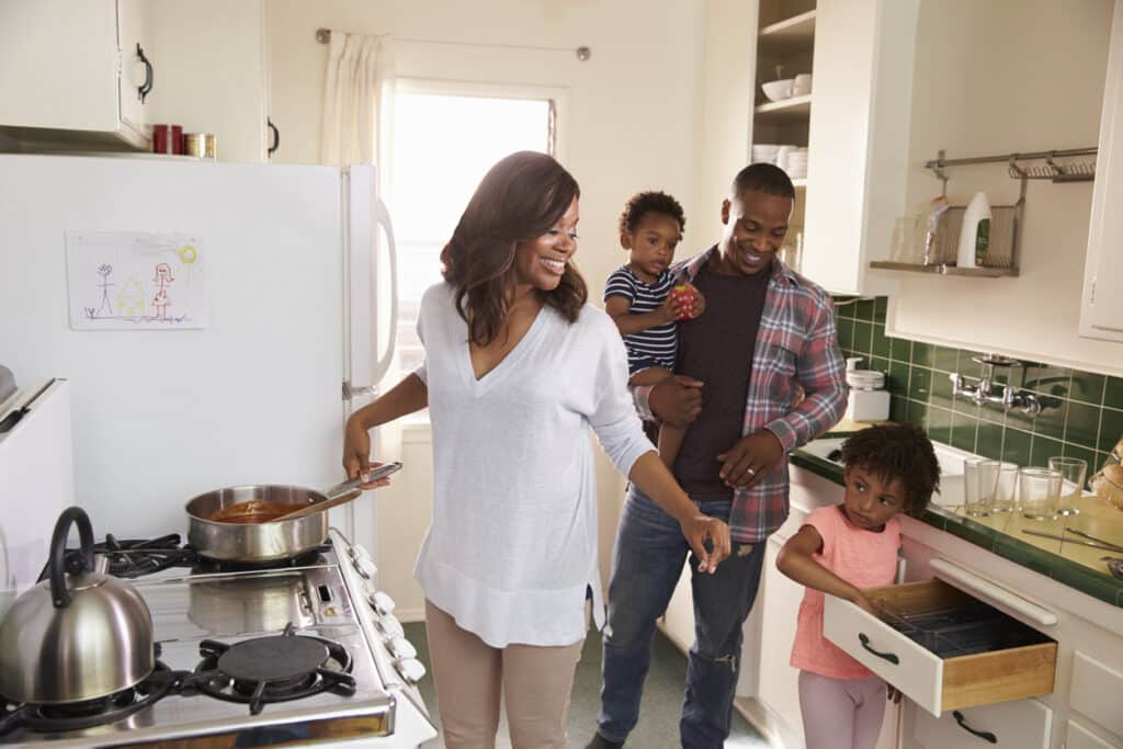 new year. Family At Home Preparing Meal In Kitchen Together