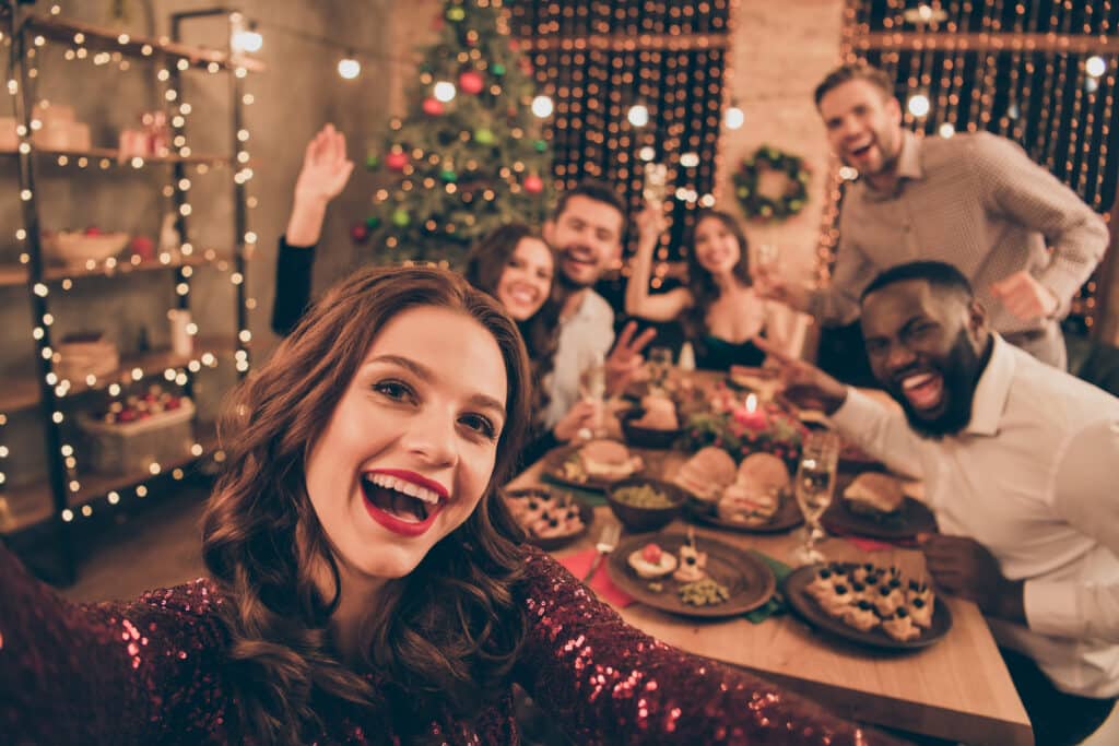 holiday party. Close up photo of cheerful fellows in formal wear sit around table enjoy, christmas party x-mas holidays making selfie in house full of noel decoration