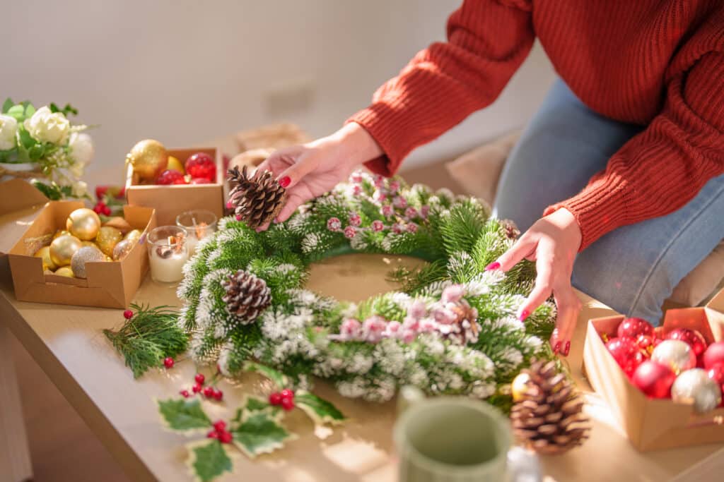 holiday decorating. Woman making mistletoe wreath Christmas wreath decoration with hand made DIY winter greenery florist hands making Christmas wreath beautiful mistletoe