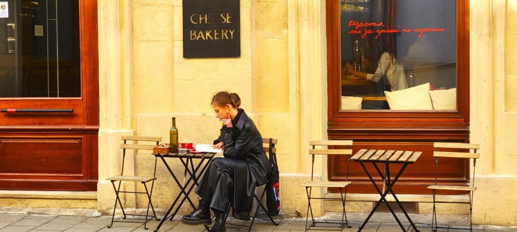 location independent retirement plan. Woman enjoying wine and reading a book at an outdoor cafe.