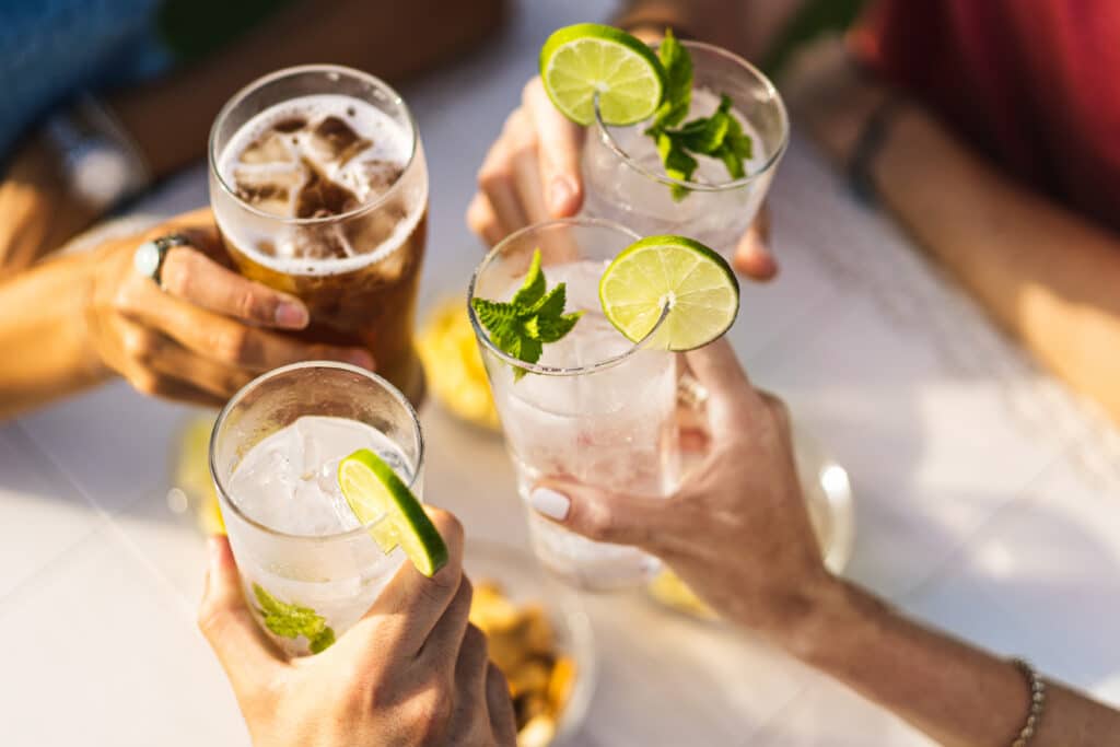 dry january, hands holding non-alcoholic cocktails with limes in them.