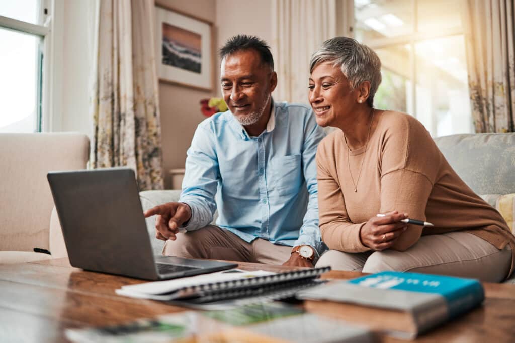 slow fi. Mature couple, sofa and laptop for planning finance, retirement funding and investment or asset management at home. Elderly people or man and woman reading information on computer for pension savings