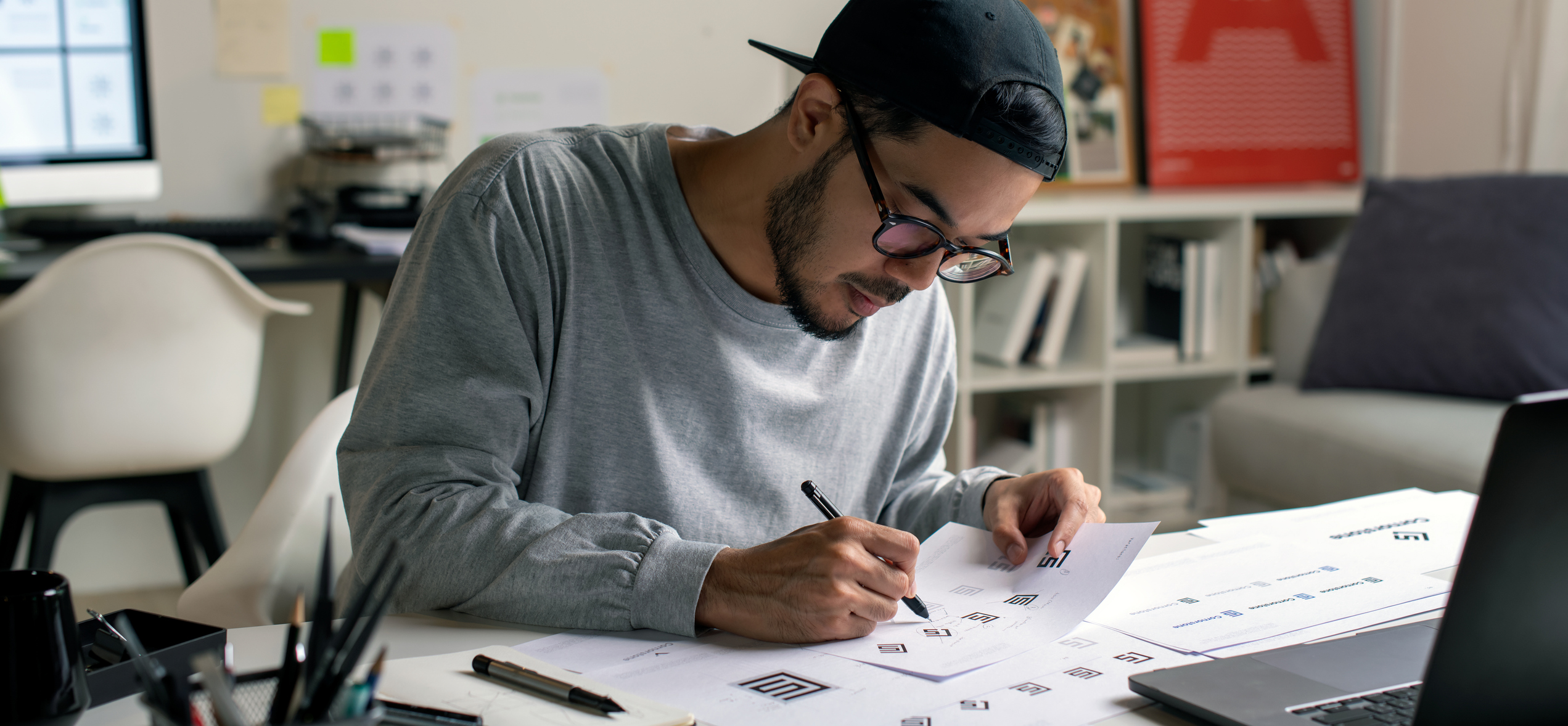 freelancer taxes. Candid shot of Asian graphic designer inspecting logo designs, using computers, designing logos, and showcasing the corporate identity and logo design process.