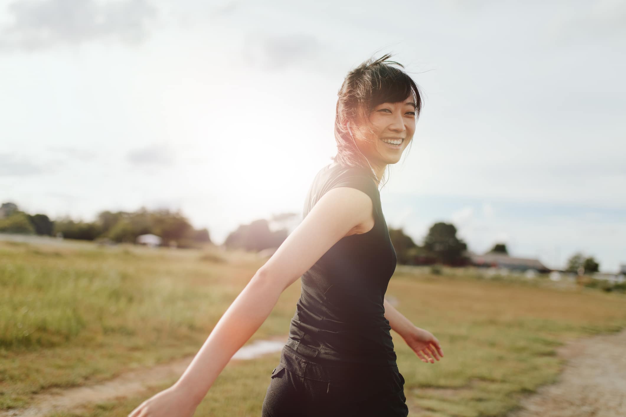 intentional living. Outdoor shot of smiling young woman runner looking at camera. Chinese female walking on field in morning.