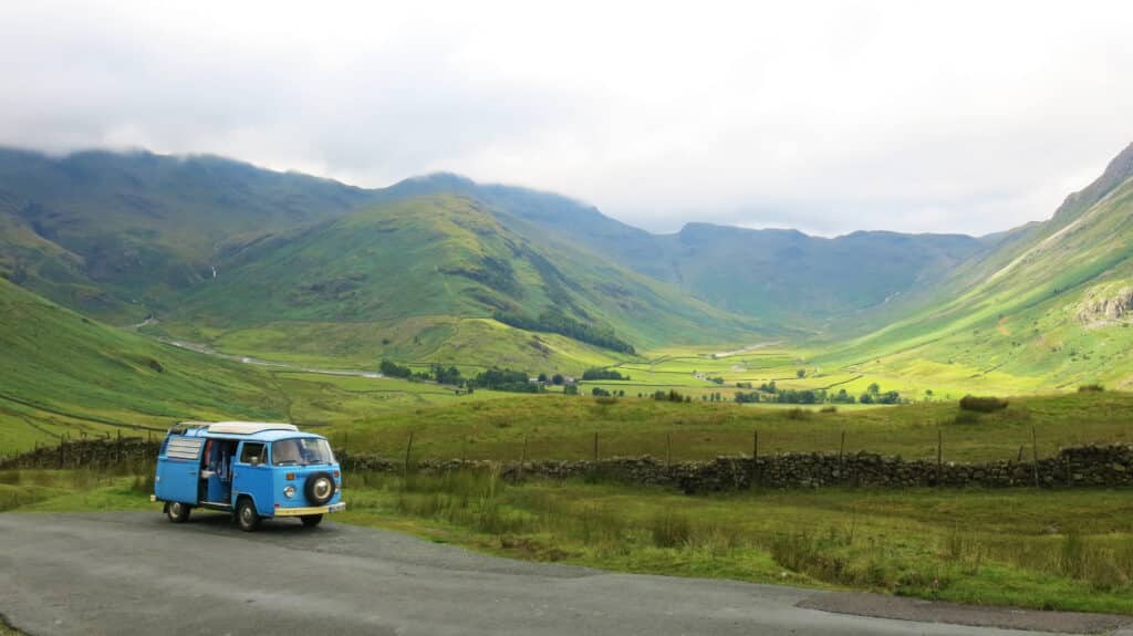 sabbatical living. Lake District National Park, Windermere, England - July, 26th, 2017:A blue classic VW Bus from 1973 driving westbound on Hawkshead passroad, one of the highest passroads in Great Britain